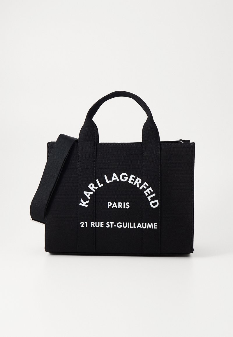 Sac cabas rectangulaire noir avec poignées courtes et bandoulière ajustable, texte blanc "Karl Lagerfeld Paris 21 Rue St-Guillaume" sur le devant.