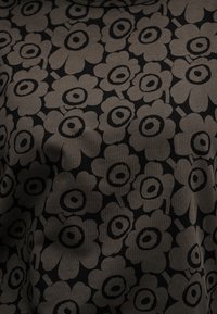 Μαύρο ύφασμα με σχέδιο μεγάλα ταουπ λουλούδια που έχουν κέντρα με κυκλικούς ομόκεντρους κύκλους, κατανεμημένα ομοιόμορφα σε όλη την επιφάνεια.