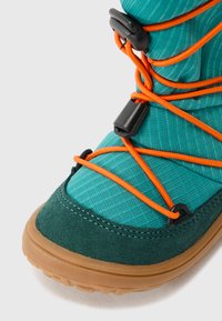 Botte en tissu teal avec des accents en daim vert foncé, des lacets élastiques orange et une semelle en caoutchouc texturée pour une meilleure adhérence et durabilité.