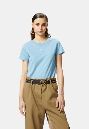 T-shirt di cotone azzurro chiaro con colletto a girocollo e maniche corte, caratterizzato da un piccolo logo ricamato. Abbinate a pantaloni beige a vita alta.