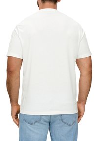 Witte katoenen t-shirt met korte mouwen, een ronde hals en een rechte zoom, gedragen met lichtblauwe denim jeans. Zichtbare naden op de mouwen en de zoom.