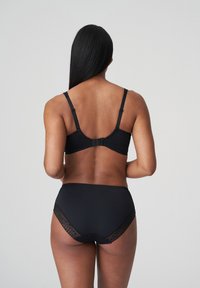 Conjunto de lencería negra que incluye un sujetador texturizado con tirantes ajustables y unas braguitas de talle alto adornadas con detalles de encaje en los bordes.