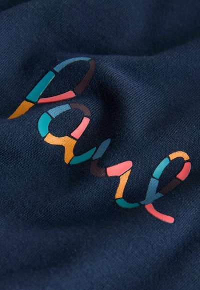 Tela azul marino con la palabra "Pausa" escrita en letras multicolores segmentadas, doblada suavemente.