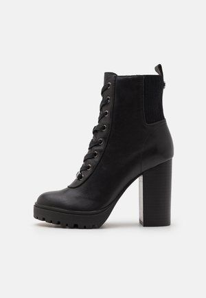 Schwarzer Leder-Stiefelette mit klobigem hohen Absatz, Schnürung vorne, elastischem Einsatz hinten und robustem Sohlenprofil.