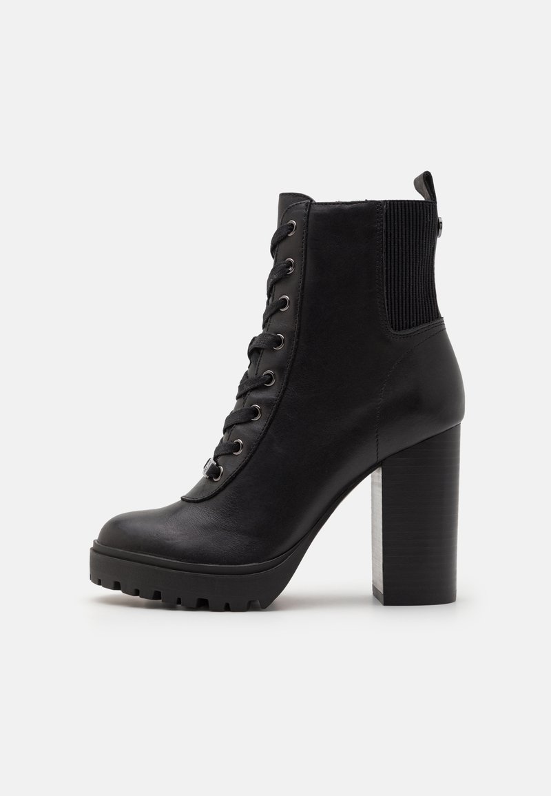 Bottine noire en cuir avec un talon haut épais, laçage sur le devant, panneau élastique à l'arrière et semelle extérieure robuste.