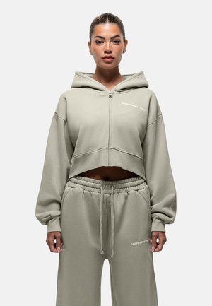 Geknipte, rits-sweatshirt en bijpassende broek van zacht, lichtgroen materiaal. Bevat logo-tekst, relaxte pasvorm en elastische tailleband.