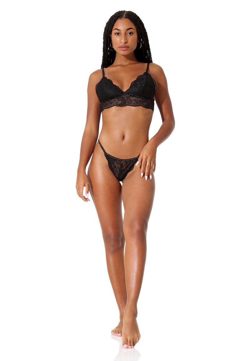 Set di bralette e perizoma in pizzo nero. Caratterizzato da bordi scallop e intricati motivi floreali. Morbida texture che completa il design delicato.