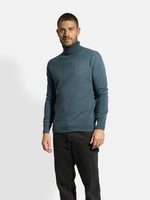 Blauwe coltrui van gebreid materiaal, met een aansluitend ontwerp en geribbelde manchetten, gecombineerd met zwarte spijkerbroek.
