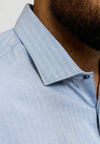 Heleheline sinine herringbone-mustriga särk, mis sisaldab teravat kraed, nööbiplokki ja sujuvat tekstuuri, et saavutada korrektne välimus.