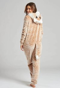 Jumpsuit a rayas de tigre en beige y crema con una capucha de felpa que presenta la cara de un león, textura suave, mangas largas y detalle de cola.