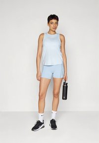 Top de desporto azul claro e calções, feitos de material respirável, combinados com ténis pretos e uma garrafa de água preta.