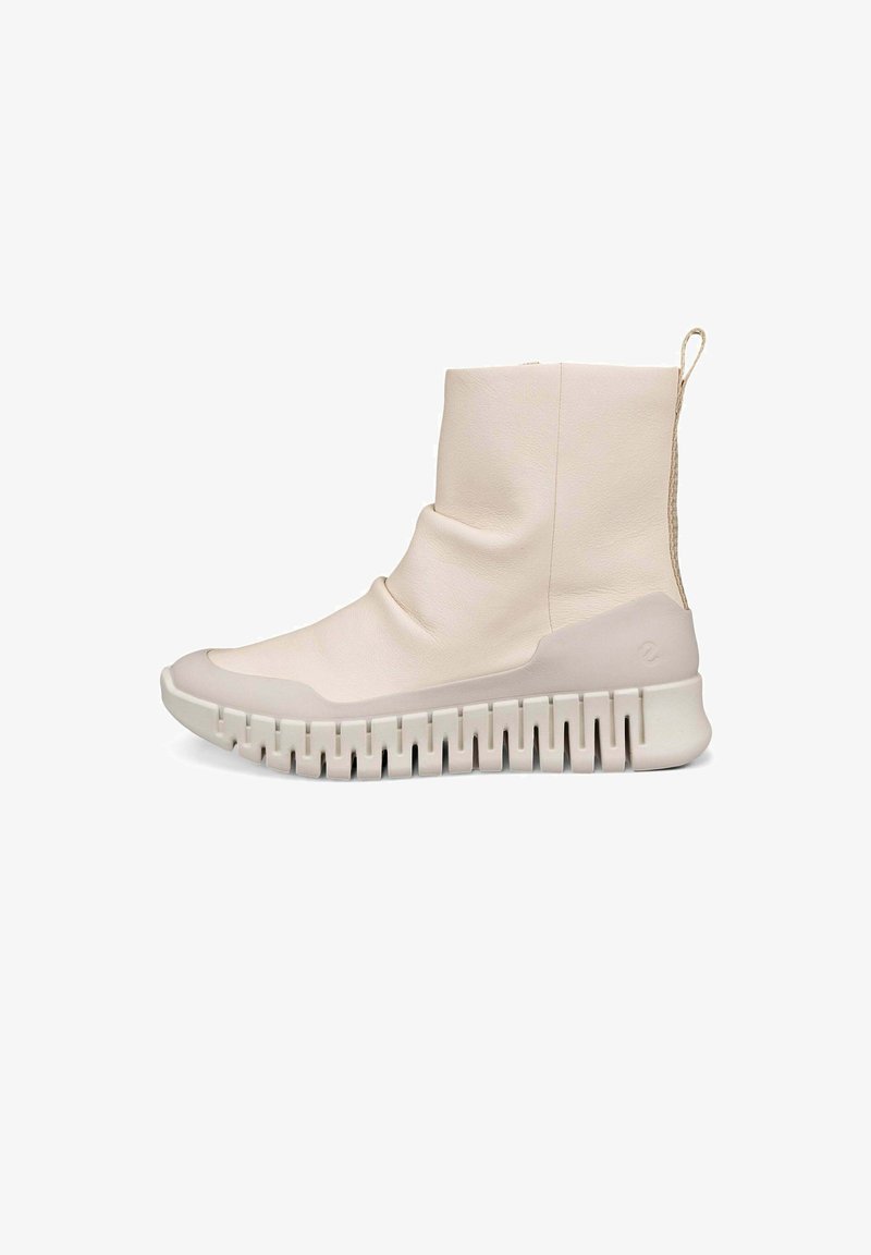 Stivaletti alla caviglia beige chiaro in pelle liscia, con una parte superiore morbida e una spessa suola in gomma bianca con un motivo scanalato.