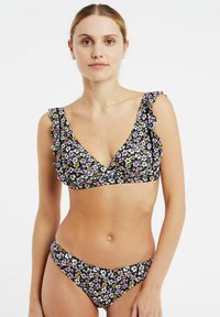 Conjunto de bikini floral con un fondo negro. La parte superior presenta detalles de volantes, un escote en V pronunciado y un estampado floral en tonos rosa, blanco y amarillo.