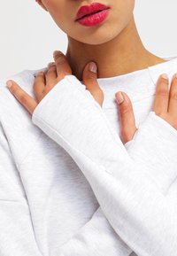 Ljusgrå sweatshirt med långa ärmar, mjuk textur och ledig passform. Har rund halsringning och märkbara sömdetaljer.