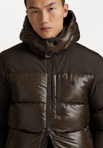 Dark brown puffer jacket featuring a quilted design, high collar, and zippered pockets with black hardware. Logo accent on chest.