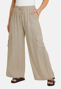 Beige vida byxor i cargo-modell med elastisk midja, dragsnöre och sidfickor. Texturerad tyg med avslappnad passform.