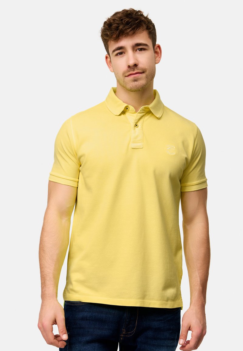 Gul polo-shirt lavet af bomuld, med en klassisk krave, korte ærmer og et lille broderet logo på brystet.