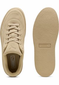 Puma sneakers i ljus beige mocka; rund tå, platta snören, vadderad tunga, texturerad gummisula med märkesinlägg; minimalistisk design.