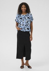 Blouse fleurie bleu clair avec des accents noirs, à manches courtes ; associée à une jupe noire longueur genoux avec une fente à l'avant. Sandales noires à choisir.