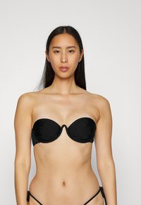 Top de bikini bandeau preto com copas moldadas, apresentando um design gather no centro e textura lisa. Sem alças visíveis.