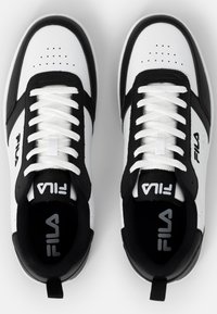 Zapatillas FILA en blanco y negro con parte superior de cuero texturizado, detalles perforados, cordones planos y suela de goma. Logotipo de la marca en la lengüeta.