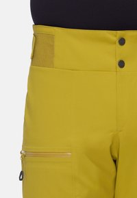 Geel waterdichte broek met een gladde textuur, voorzien van een ritszak en drukknoopsluitingen. Inclusief een aangesloten taillebandontwerp.