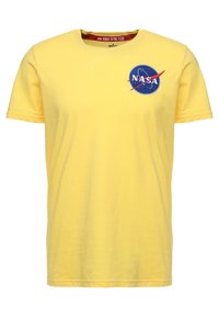 Žluté tričko s krátkým rukávem a kulatým výstřihem, s modrým logem NASA na levé straně hrudi a červeným textem uvnitř límce.
