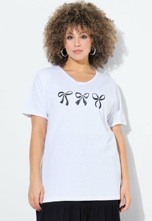 T-shirt en coton blanc avec trois graphiques de nœuds noirs sur la poitrine. Manches courtes et encolure ronde. Texture douce.