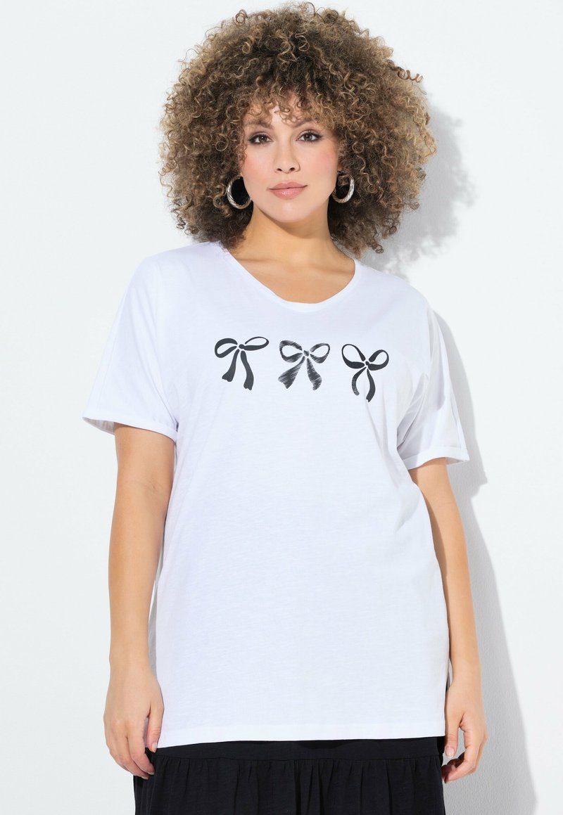 T-shirt en coton blanc avec trois graphiques de nœuds noirs sur la poitrine. Manches courtes et encolure ronde. Texture douce.