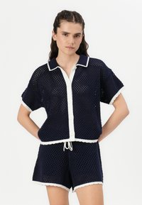 Set da lounge in maglina blu navy composto da una camicia corta con maniche corte e bottoni, rifinita con bordi bianchi, abbinata a pantaloni corti con orlo scallop.