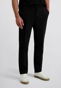 Zwarte taps toelopende broek met een trekkoord in de taille, voorzien van zijkanten zakken en een soepele katoenmix stof voor comfort en flexibiliteit.