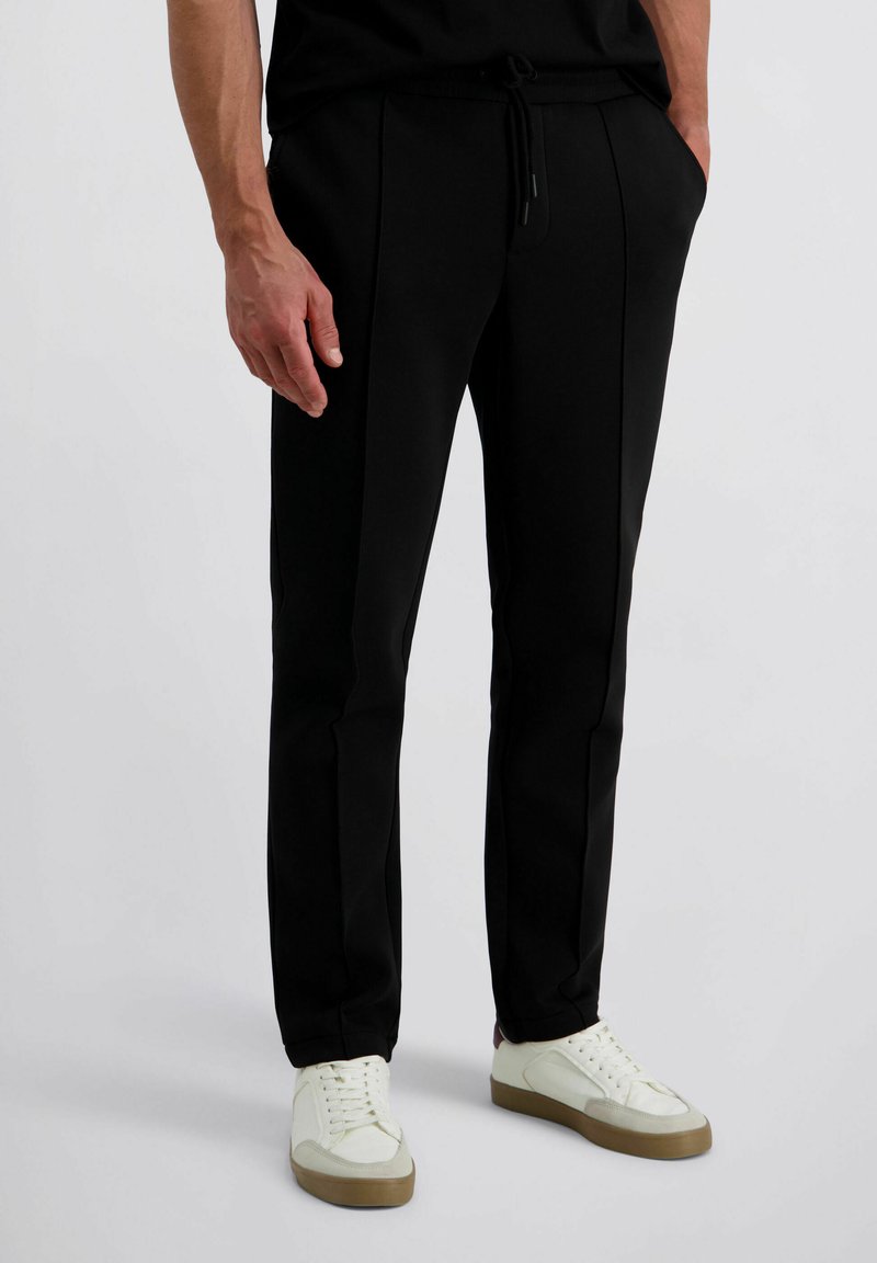 Zwarte taps toelopende broek met een trekkoord in de taille, voorzien van zijkanten zakken en een soepele katoenmix stof voor comfort en flexibiliteit.