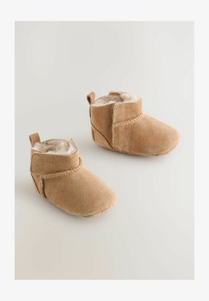 Barna velúr csizmák puha szőrme béléssel, alacsony csizmavágással, és varrott díszítéssel a bokán, hátul pedig húzószalaggal.