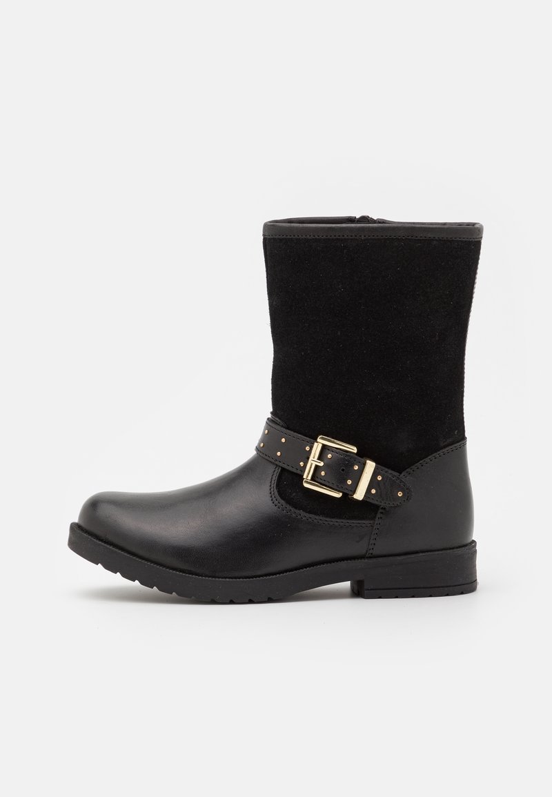 Botte noire mi-mollet avec pied en cuir lisse, dessus en daim, bride décorative à boucle dorée et talon bas à bloc sur fond blanc.