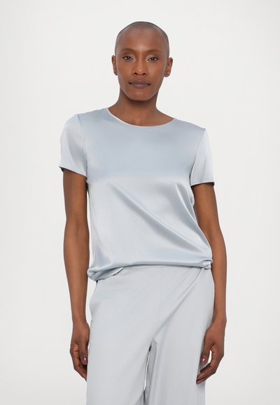 Top curto de cetim azul claro com mangas curtas, decote arredondado, caimento suave e textura lisa, combinado com calças largas azuis claras a condizer.