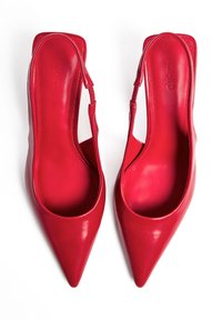 Talons aiguilles en cuir rouge avec une forme slingback, texture lisse et design minimaliste. Comprend une fine bride de cheville pour un soutien.