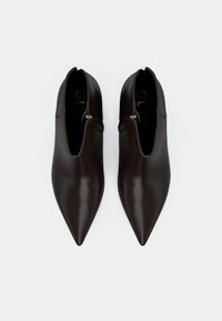 Botine din piele maro închis cu vârf ascuțit, textură netedă, închidere cu fermoar pe lateral și o marcă discretă în interior.