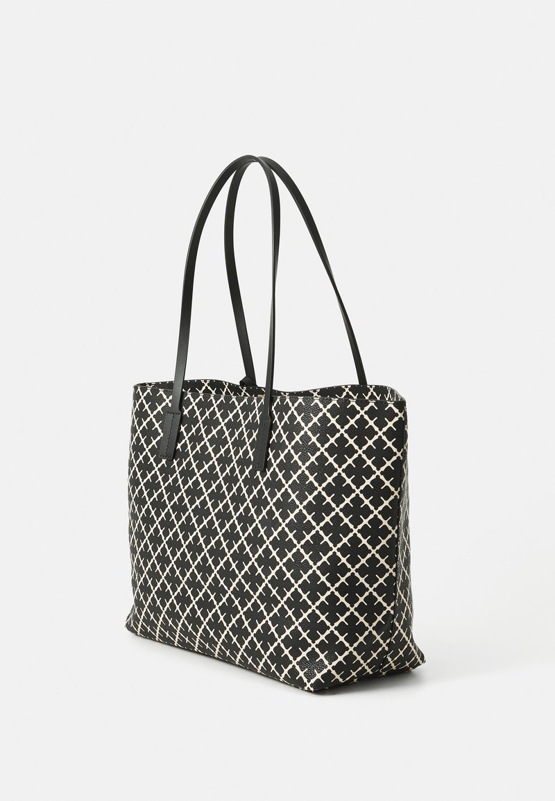 Svart och krämfärgad shoppingväska med geometriskt mönster, tillverkad av hållbart material, med långa svarta handtag och en strukturerad form.