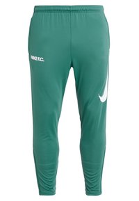 Tealfärgade slim-fit Nike F.C. sportbyxor med elastiskt midjeband och vit Nike swoosh på höger lår samt "NIKE F.C." text på vänster lår.
