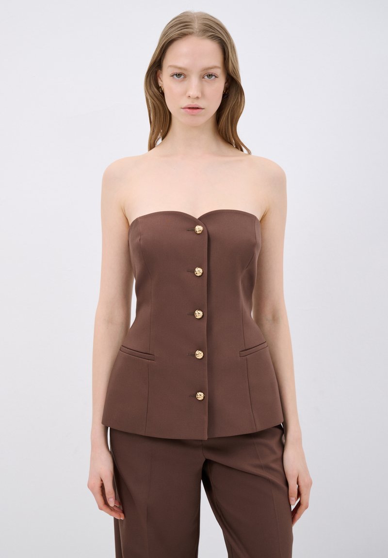 Top marrone senza spalline con scollatura a forma di cuore, caratterizzato da sei bottoni dorati sulla parte anteriore e due tasche laterali. Tessuto dalla texture liscia.