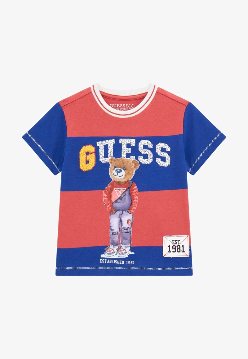 Red and blue short-sleeve cotton t-shirt featuring a bear graphic, "GUESS" name, and "EST. 1981" tag at the hem. Crew neck design.