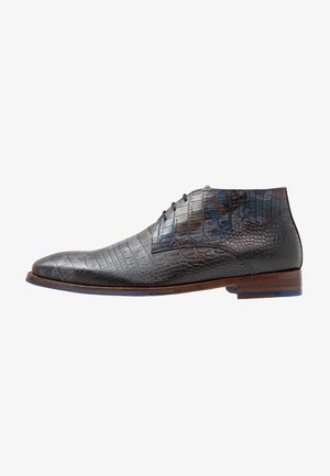 Bottes en cuir bleu foncé avec une texture crocodile. Dotées d'un bout arrondi, d'une semelle en bois brun et d'un système de laçage.