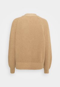 Beige stickad tröja med rundad halsringning, raglanärmar och ribbade muddar. Strukturerad tyg med lös passform och subtilt mönster.