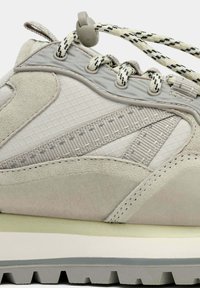 Baskets gris clair avec une tige en mesh et suède, des accents texturés, des lacets élastiques, une semelle rembourrée et une semelle extérieure en caoutchouc rainurée.