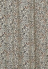 Tkanina w wzór panterki na kremowym tle, z małymi czarnymi i brązowymi plamami, gładka w dotyku i z plisowanym wzornictwem.
