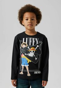 Schwarzes Langarmshirt mit einem grafischen Druck eines Charakters mit einem Strohhut und einem Totenkopf, kombiniert mit blauen Jeans und einem lässigen Schnitt.