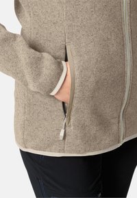 Giacca a maglia color crema con finitura strutturata, dotata di tasca con zip e rifiniture chiare a contrasto lungo il fondo e i polsini.