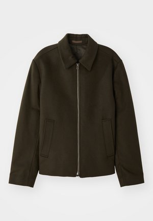Dunkelgrüne Zip-Jacke aus einem weichen, strukturierten Stoff. Verfügt über einen Kragen und zwei seitliche Taschen mit einem schlichten, minimalistischen Design.