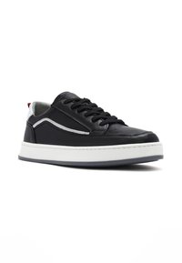 Czarne skórzane sneakersy z białą gumową podeszwą, okrągłym noskiem, czarnymi sznurowadłami i srebrnym akcentem wzdłuż. Posiadają wyściółkę kołnierza oraz kontrastowy detal na obcasie.