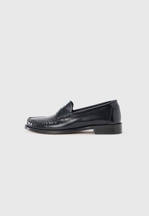 Black leather loafer featuring a rounded toe, decorative stitching, and a low block heel. Smooth texture, minimal accents.